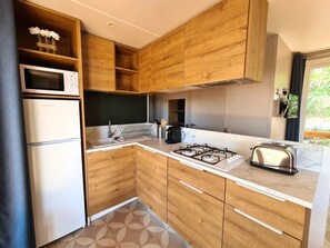 Eine moderne Küche mit Holzschränken, einer Mikrowelle, einem Kühlschrank, einem Gasherd und einem Toaster.