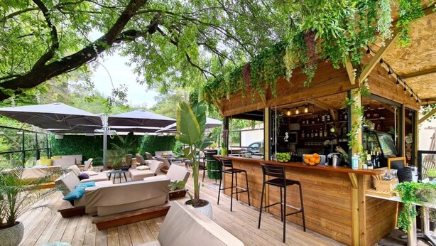 Un patio al aire libre con suelo de madera, una barra y arreglos de asientos.
