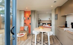A compact hotel room with a kitchenette, a dining area, and a bed. - Camping 4 étoiles - Piscine  - ccbfibf (Carqueiranne)