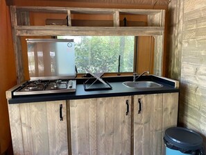 Eine kleine Küche mit Gaskochfeld, Spüle und Holzschränken.