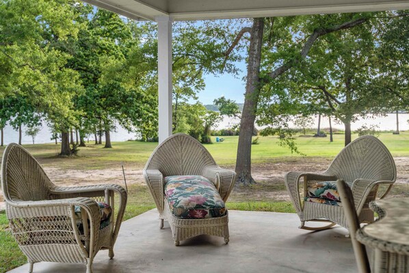 A covered patio with wicker furniture and a view of a lake. - Peaceful Lakeside Serenity on Lake Palestine (Coffee City)