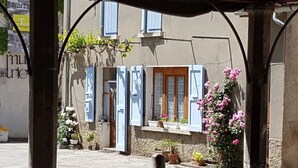 A building with blue shutters, a wooden door, and potted plants. - Camping 3 étoiles - Piscine  - ccbgaad (Mens)
