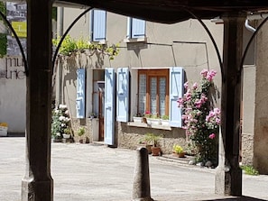 A building with blue shutters, a wooden door, and potted plants. - Camping 3 étoiles - Piscine  - ccbgaad (Mens)