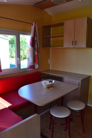 Een kleine keuken met een zithoek, inclusief een tafel, twee krukken en een bank.