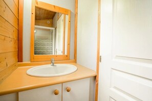 Une salle de bain avec un meuble-lavabo en bois, un lavabo blanc et un miroir.