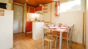 Cocina compacta con comedor, techo de madera y ventana con cortinas.