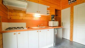 Kompakti keittiö, jossa on valkoiset kaapit, ruostumattomasta teräksestä valmistettu astianpesukone, kaasuliesi ja mikroaaltouuni.