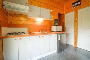 Een compacte keuken met witte kastjes, een roestvrijstalen vaatwasser, een gasfornuis en een magnetron.