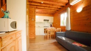 Ein Holzblockhaus-Interieur mit Küchenzeile, Essbereich und einer Couch.