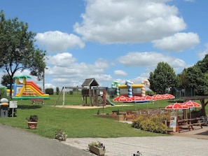 Ein Spielplatz mit Hüpfburgen und einer kleinen Holzkonstruktion.