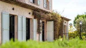 Un edificio con varias ventanas, algunas con persianas, y un balcón con barandilla.