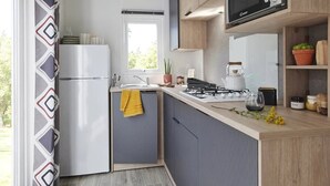A modern kitchen with a built-in stove, a refrigerator, and a window. - Camping 3 étoiles - Piscine  - ccbgadc (Illiers-Combray)