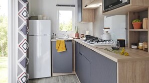 Eine moderne Küche mit Einbauherd, Kühlschrank und Fenster.