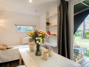 Ein modernes Zimmer mit einem Esstisch, einer Blumenvase und Blick ins Freie.