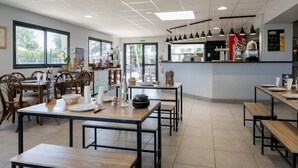 Un interior de restaurante moderno con varias mesas, sillas y una barra.