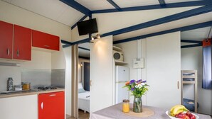 Habitación compacta con kitchenette, comedor con una mesa para dos personas y una cama al fondo.