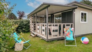Un espacio al aire libre techado con una mesa, sillas, una pelota de playa y un pequeño edificio con una ventana.