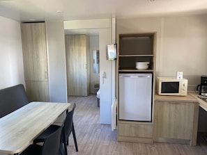 Eine kleine Küche mit einer Mikrowelle, einem kleinen Kühlschrank und einem Holzkorpus.