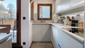 Una cocina moderna con ventana, armarios blancos y techo de madera.