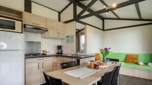 Una cocina compacta con comedor, microondas, estufa y pileta.