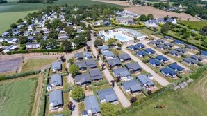 Vista aérea de una zona residencial con varias casas, una piscina y campos verdes.