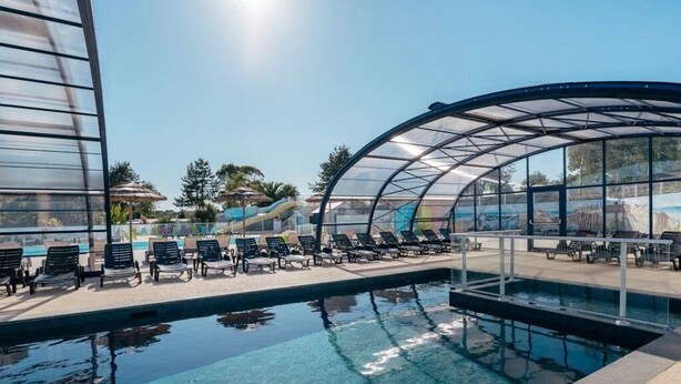 Una piscina con sillas de descanso y una zona cubierta.