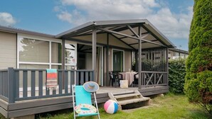 Un espacio al aire libre cubierto con una terraza, una silla con cojín y una pelota de playa.