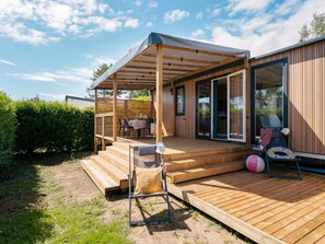 Eine Holzterrasse mit überdachter Sitzgelegenheit, einem Pool und einer Liege.