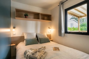 Ein Schlafzimmer mit Bett, Nachttischlampen, einem Fenster mit Blick und einem Regal mit Pflanze.