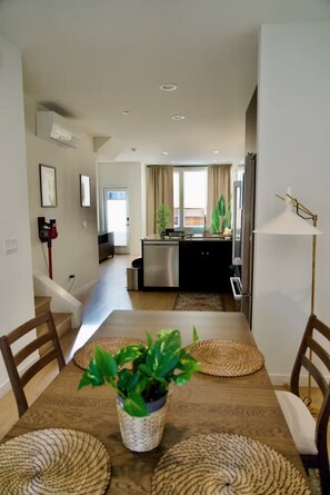A modern kitchen with a central island, a dining area with a wooden table and chairs, and a staircase leading to another level. - 3-bedroom townhome in peaceful Seattle with AC for relaxing stays (Seattle)