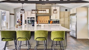 A kitchen with a large island, bar stools, hanging pendant lights, and modern appliances. - Mtn Views, Game Room, Near Dollywood & Gatlinburg, Firepit, Hot Tub, Bunk Beds (Sevierville)