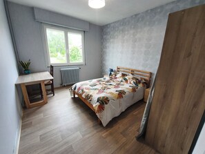 Une chambre Ă coucher avec un lit, un bureau, un radiateur et une fenĂȘtre.