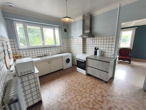 A kitchen with a washing machine, oven, and a window with a view of greenery.