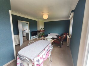 Un coin repas avec une table dressée pour deux personnes, un téléviseur et un canapé, le tout dans une piÚce aux murs de couleur turquoise.