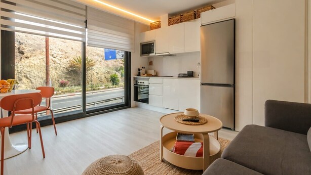 A modern kitchen with white cabinets, a built-in oven, and a large refrigerator. - Sunset Loft By CanariasGetaway (Mogán)