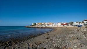 A rocky beach with buildings in the background. - Sunset Loft By CanariasGetaway (Mogán)