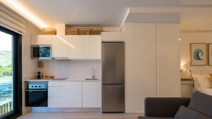 A modern kitchen with white cabinets, a stainless steel refrigerator, and a microwave. - Sunset Loft By CanariasGetaway (Mogán)