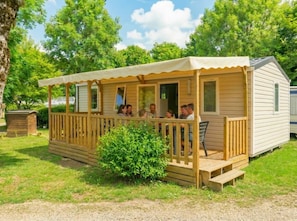 Eine kleine Holzhütte mit Veranda, überdachter Terrasse und einem kleinen Garten.