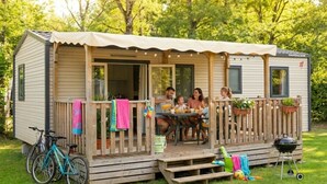 Una casa móvil con terraza, asientos exteriores, una parrilla y una bicicleta.