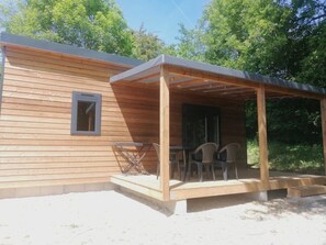 Una cabana de fusta amb un porxo cobert, una taula i cadires.