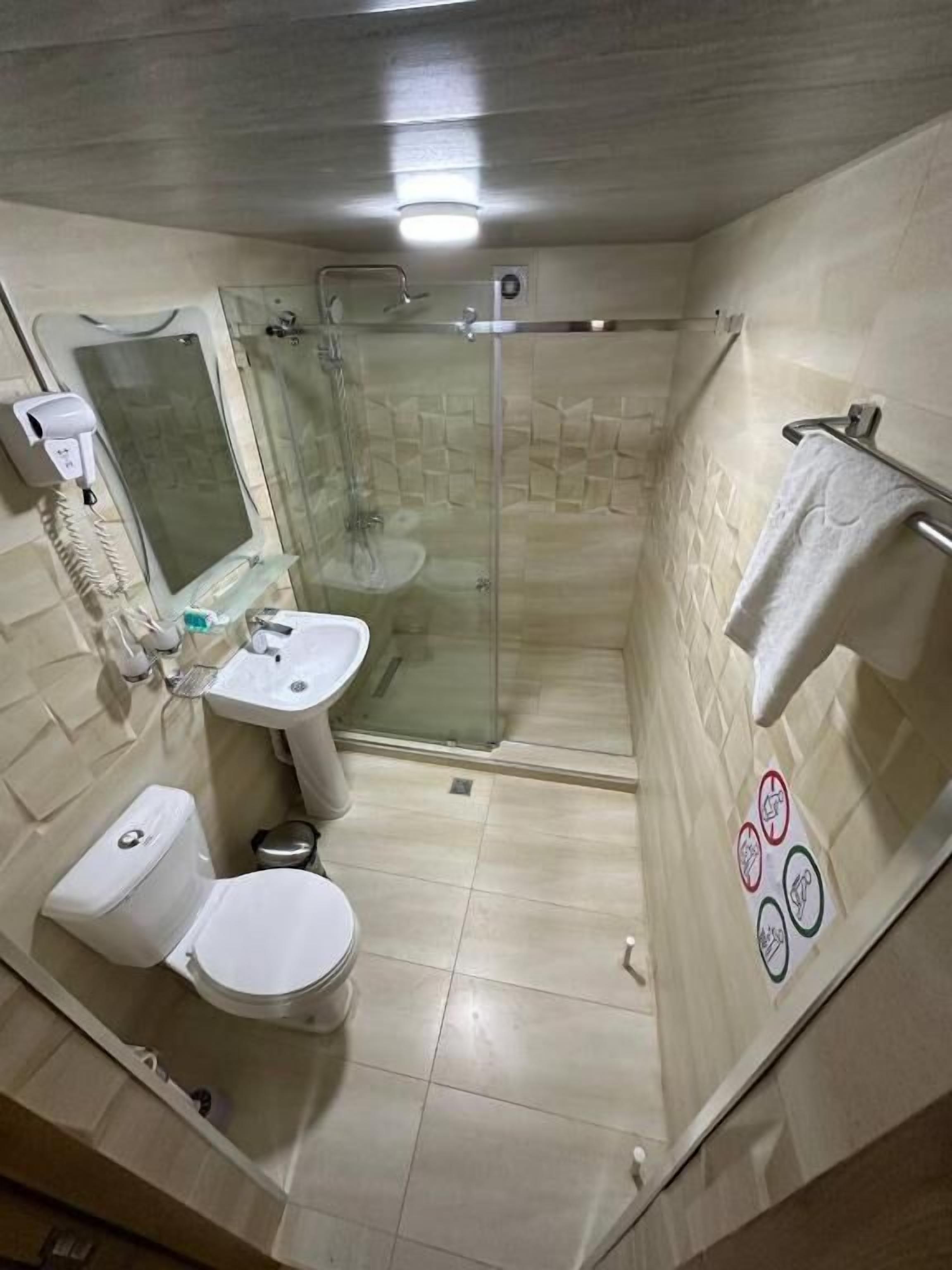 A bathroom with a toilet, sink, and shower.