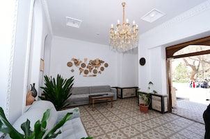 A room with a patterned floor, a chandelier, a sofa, and potted plants.
