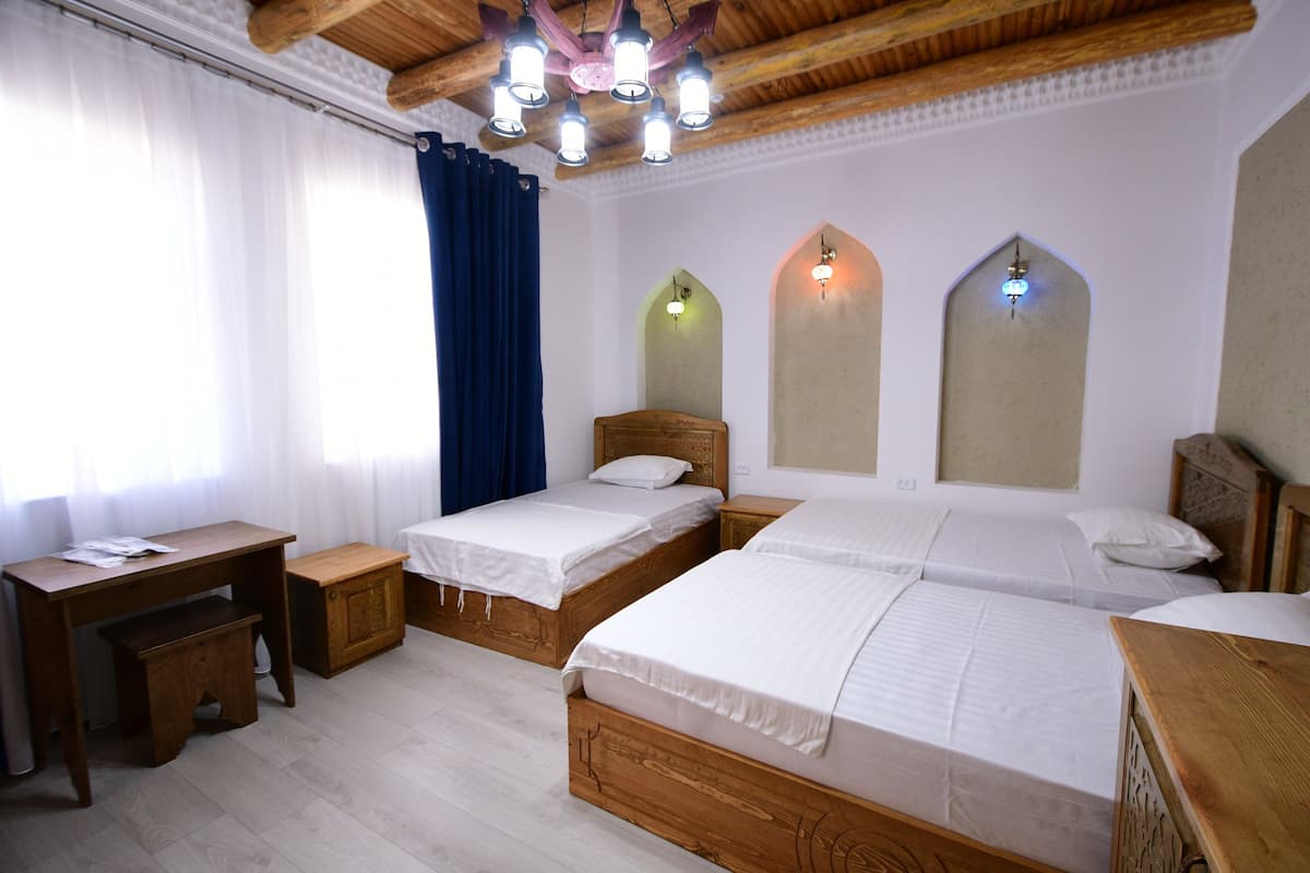 A room with two wooden beds, a desk, and a small cabinet.