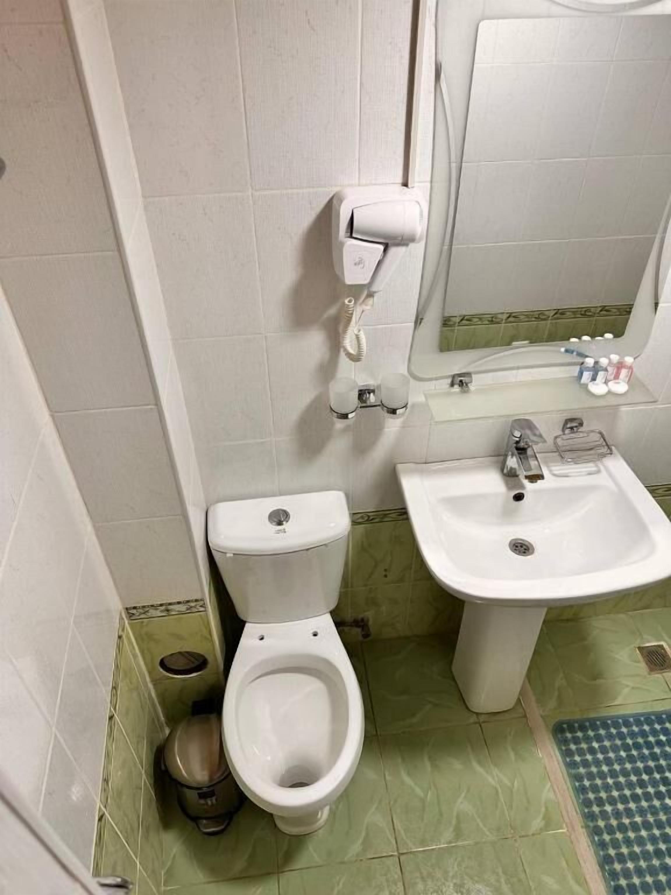 A bathroom with a toilet, bidet, sink, and mirror.