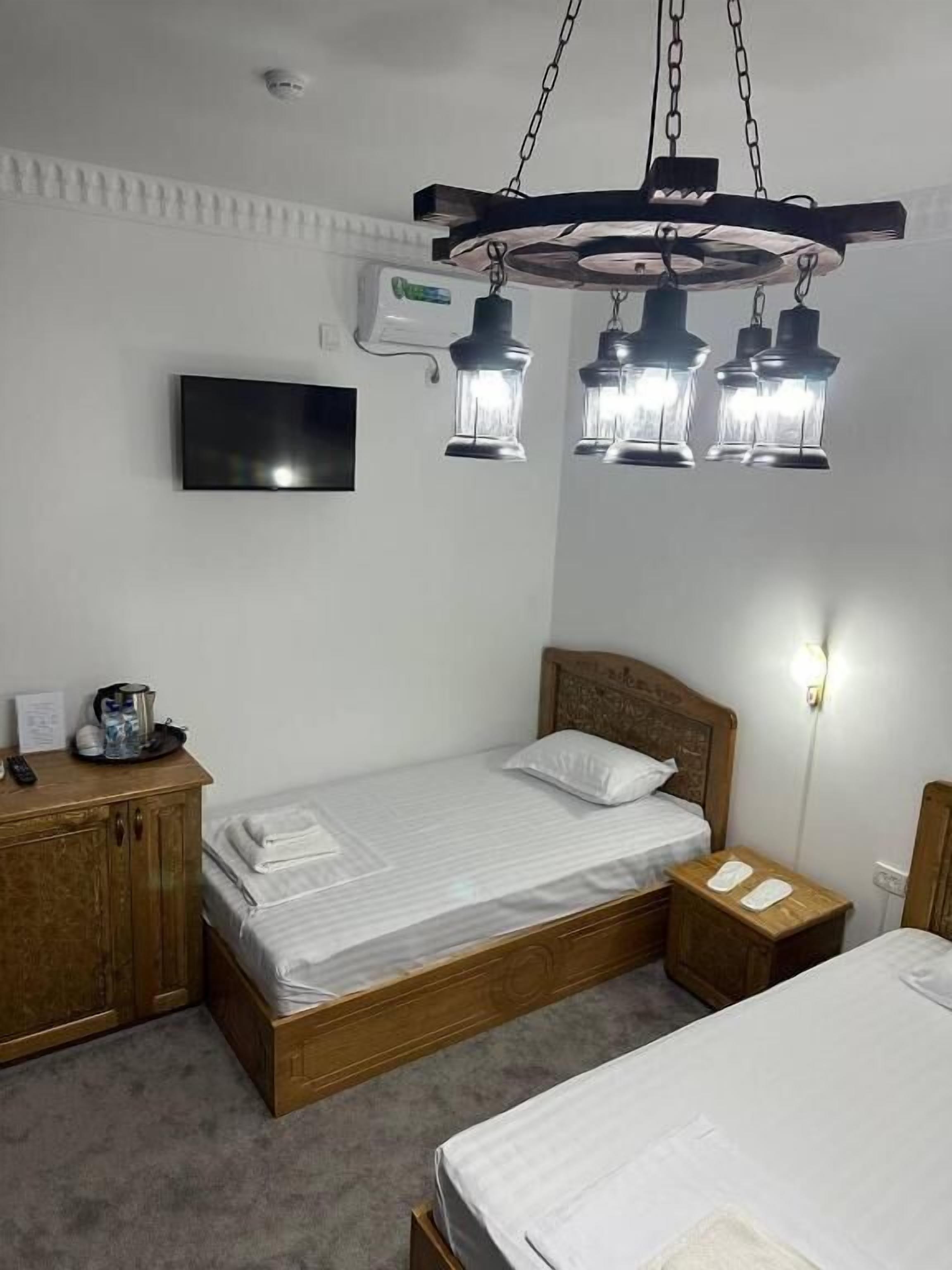 En enkeltseng med trægavl, et natbord med lampe og et tv ophængt på væggen.