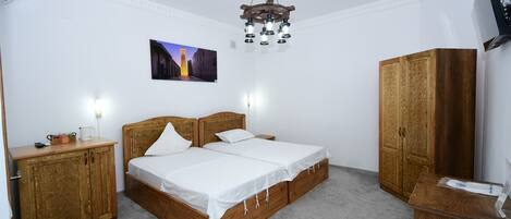 A bedroom with a double bed, wooden wardrobe, and a mounted TV.