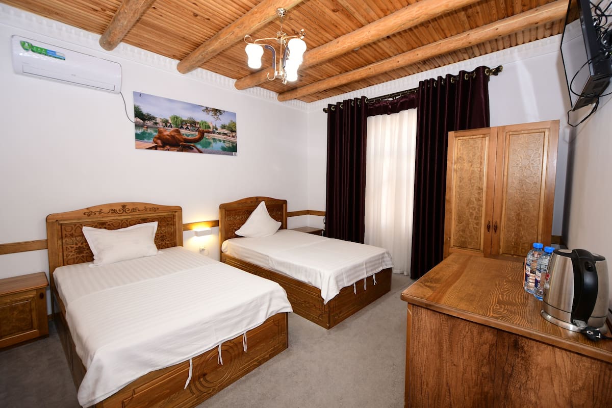 A room with two wooden beds, a wooden desk, a kettle, and a water dispenser.