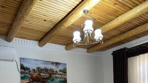 Una habitación con dos camas de madera, un candelabro, un cuadro en la pared y una ventana con cortinas.