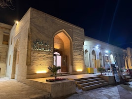 A hotel with a stone facade, an arched entrance, and a sign indicating a restaurant.