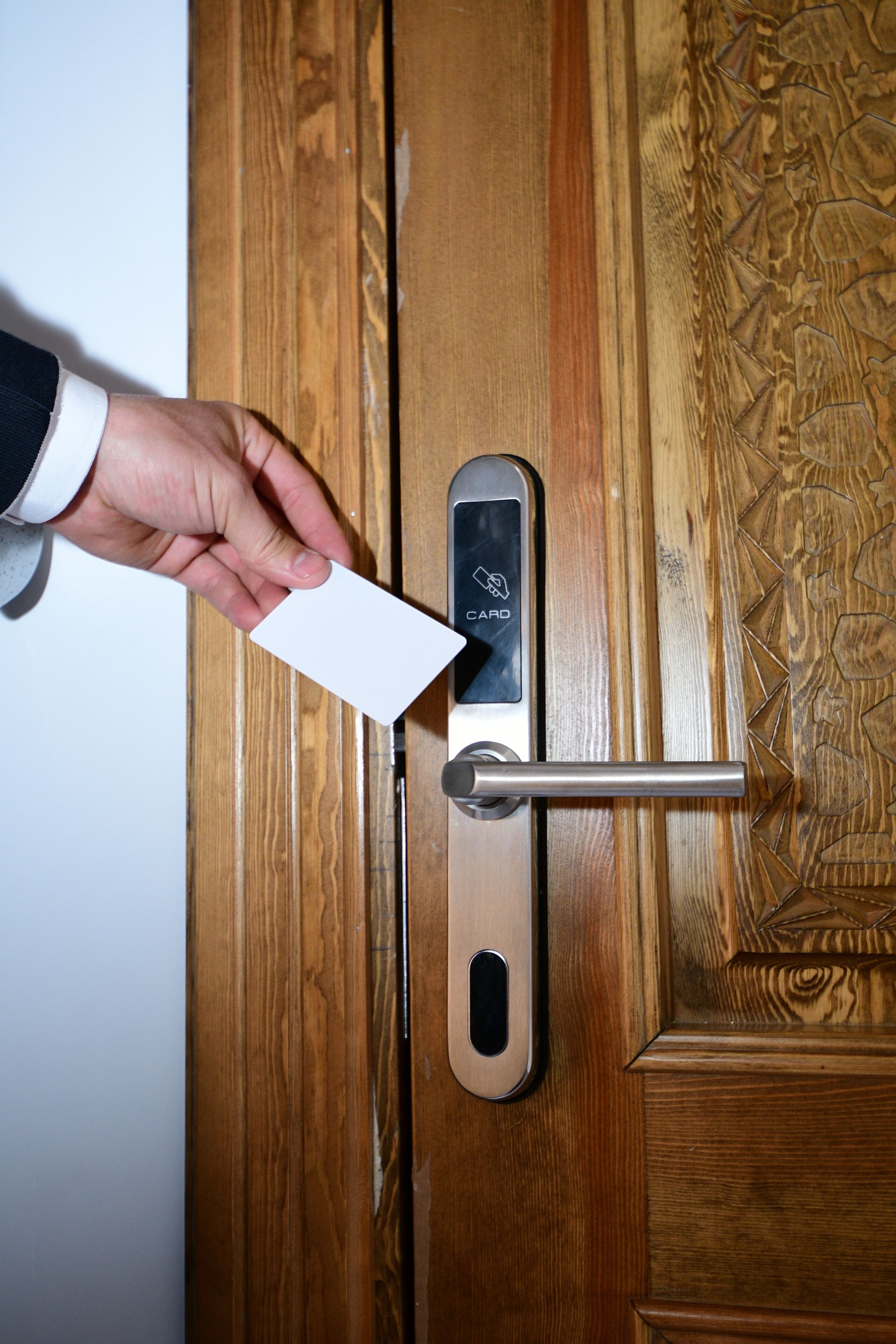 A hand inserting a card into a card reader on a wooden door.